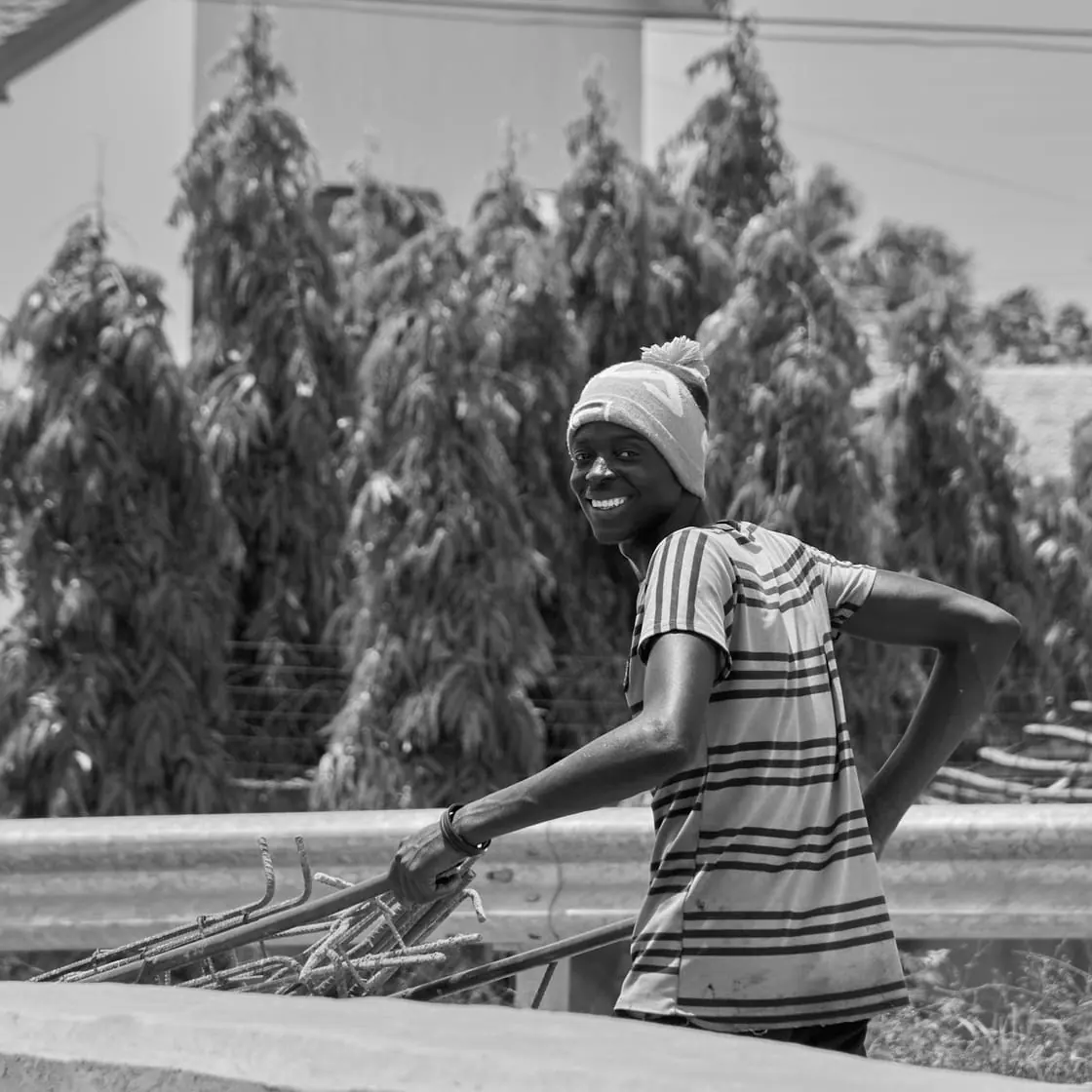 Foto en blanco y negro de un joven con gorro y camiseta de rayas apoyado en la barandilla de una azotea.