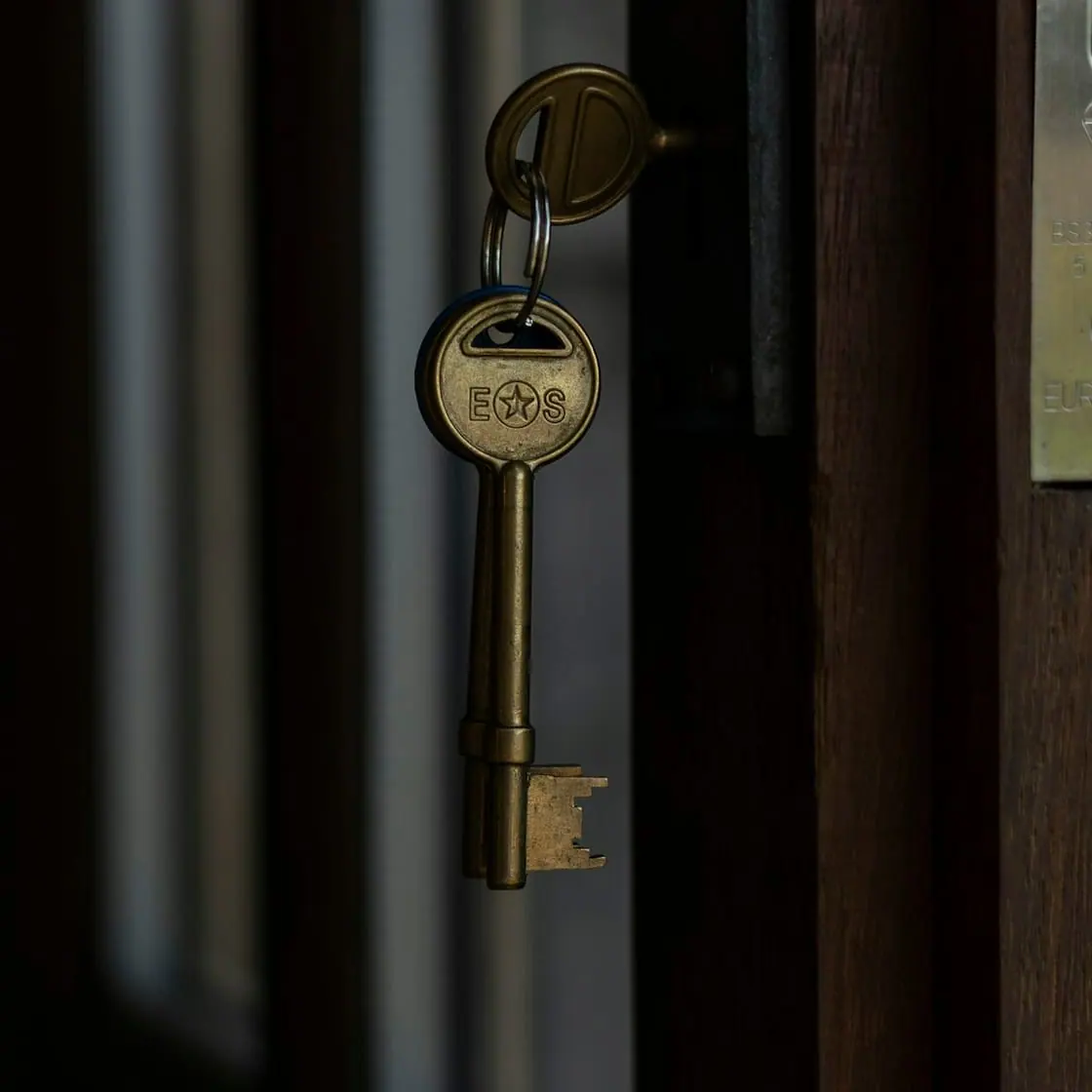 Una llave antigua metida en la cerradura de una puerta en penumbra.