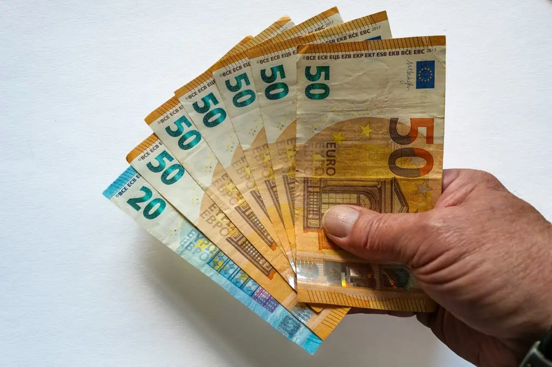 Una mano sujeta en abanico varios billetes de 50 euros y uno de 20.