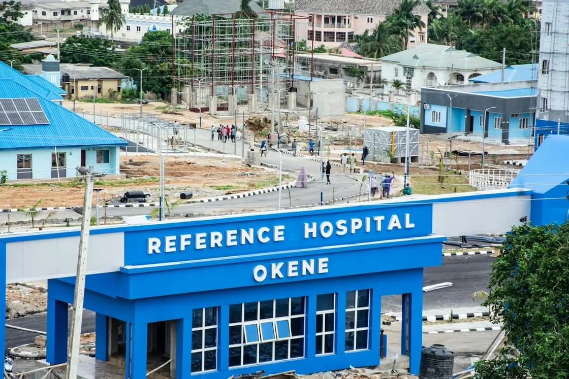 La entrada azul de un hospital vista desde lo alto, con edificios y obras alrededor.