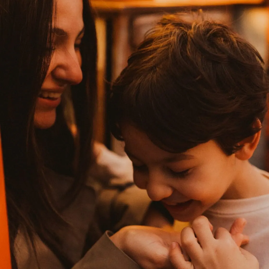 Una madre y su hijo pequeño se ríen abrazados.