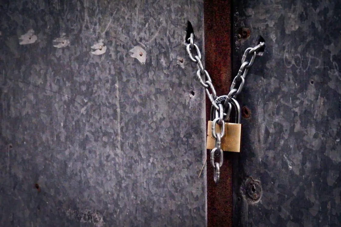 Una puerta metálica cerrada con una cadena y un candado.
