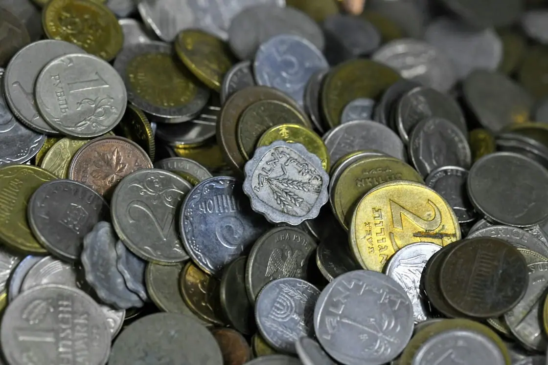 Un montón de monedas de distintos países y tamaños, vistas de cerca.
