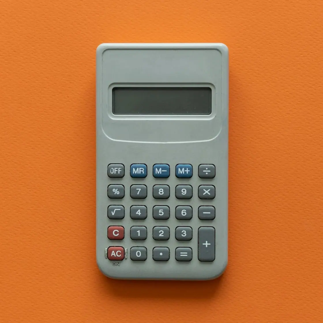Una calculadora gris sobre un fondo naranja.